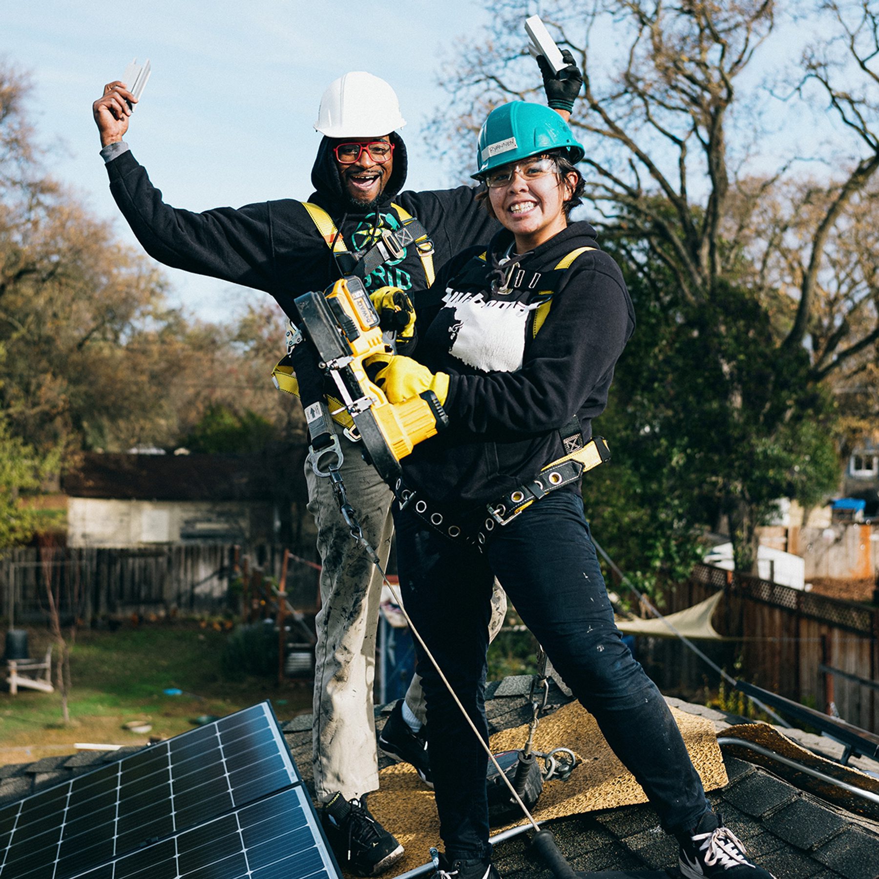 two smiling solar panel workers on top of a solar roof