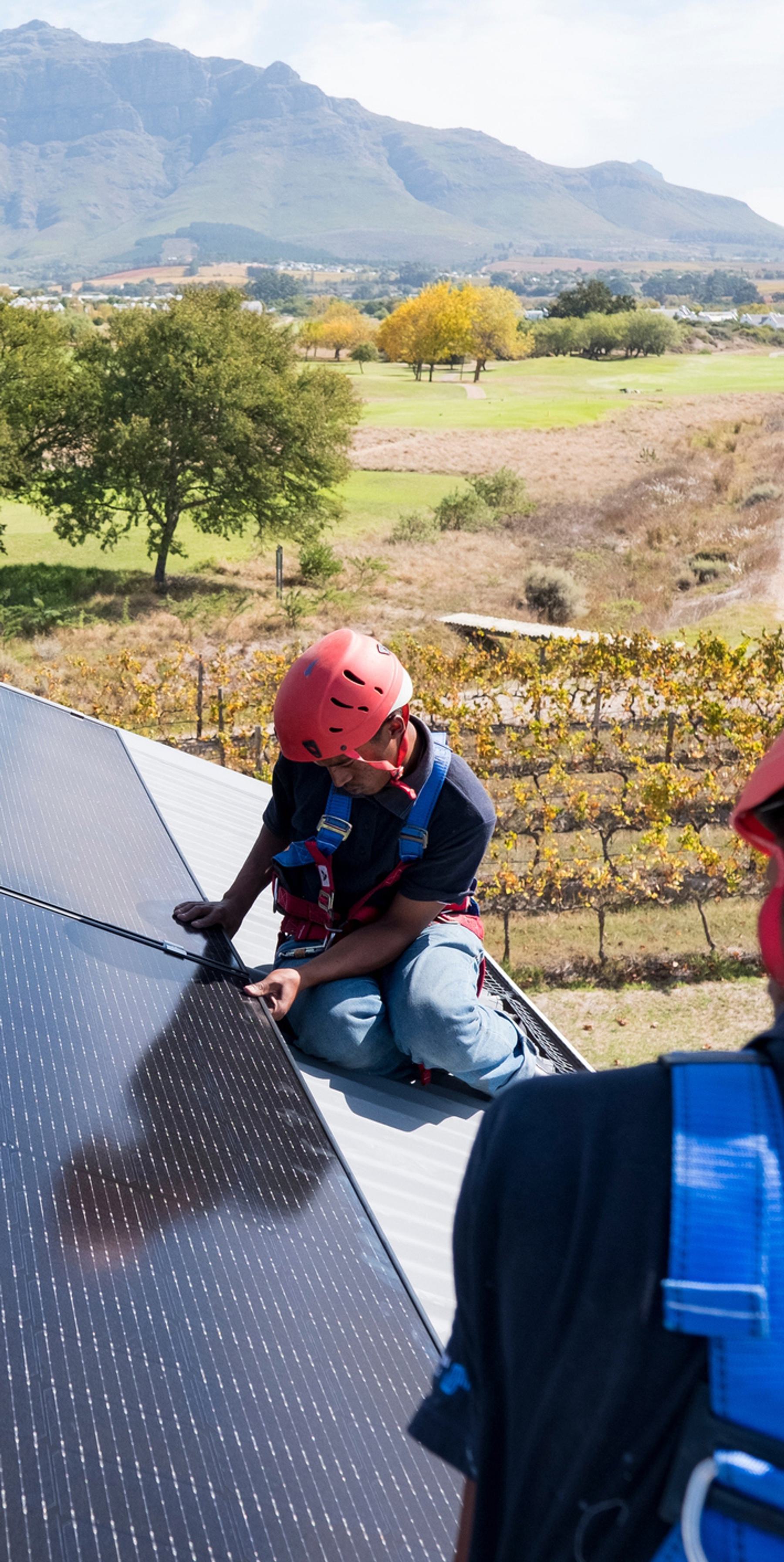 two men working on a solar panel with a field in the background